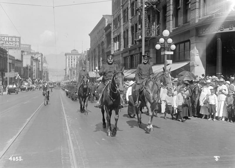 Riders in uniform lead a parade along Granville Street, past crowds on the sidewalk