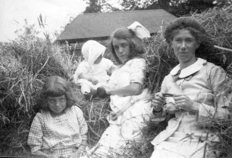 A woman and three children sitting in the long grass in the yard of 2890 Point Grey Road